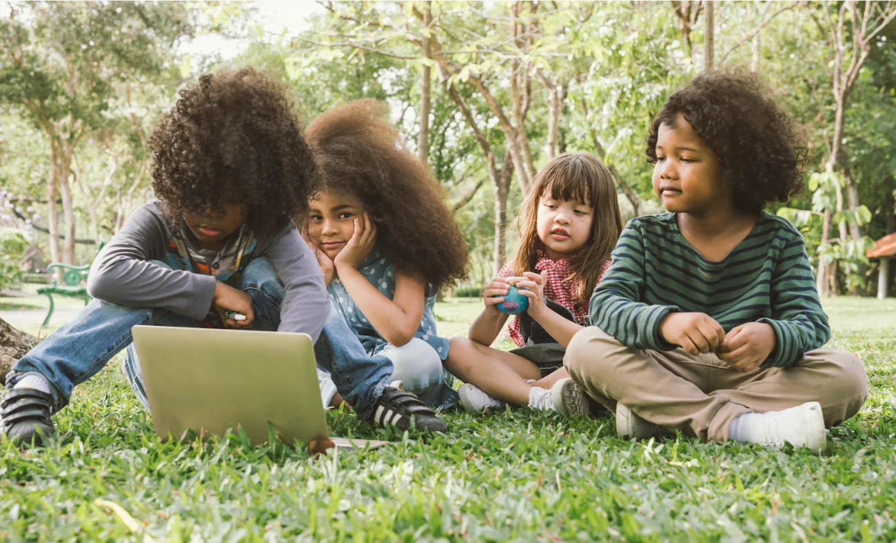 children around a laptop outside